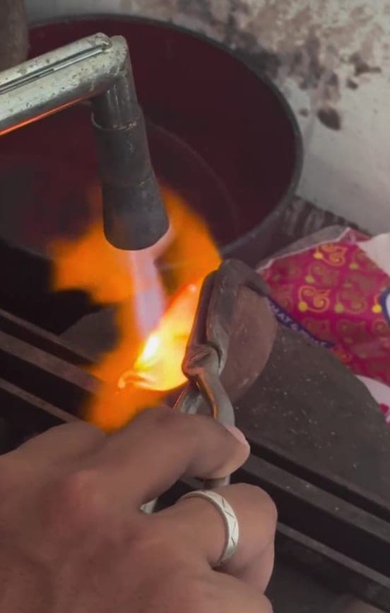 Soldering a silver ring with a torch at the Kuta Jewellery Silver Class workbench